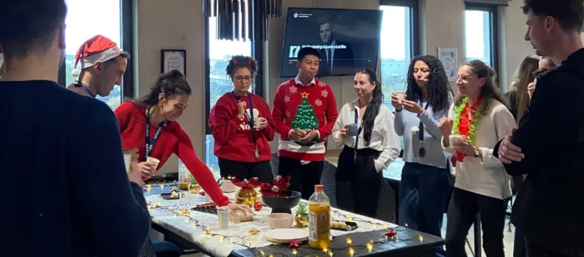 Résidents en espace de coworking portant des pulls de Noël lors d’un événement de fin d’année.