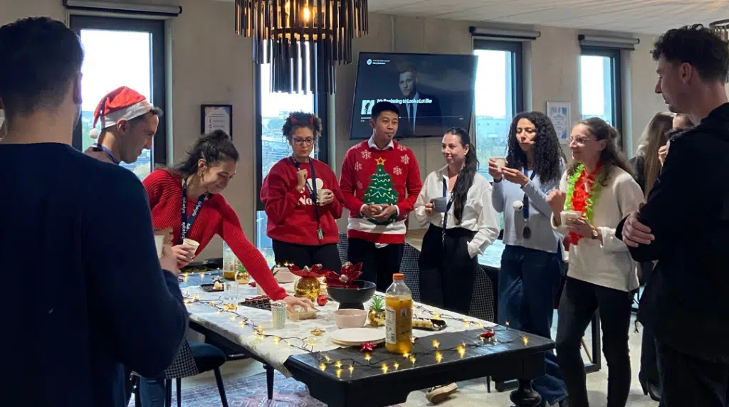 Résidents en espace de coworking portant des pulls de Noël lors d’un événement de fin d’année.